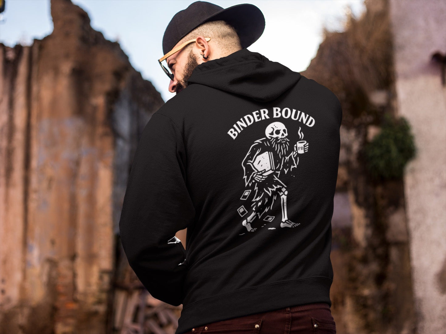 Person wearing a black hoodie with 'Binder Bound' graphic design outdoors.