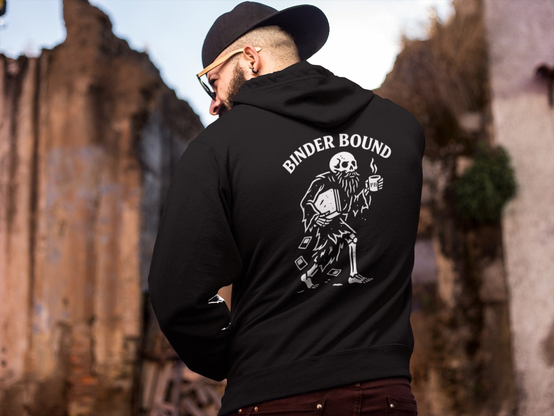 Person wearing a black hoodie with 'Binder Bound' graphic design outdoors.