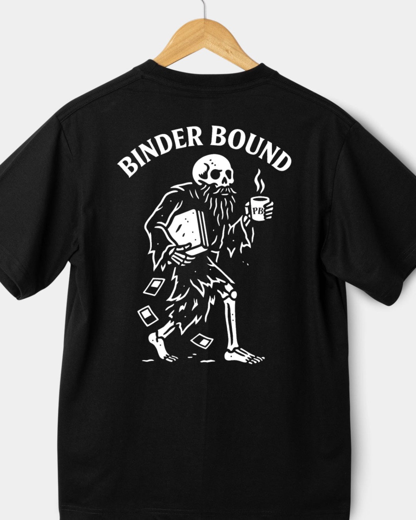 Black t-shirt with a skeleton holding a binder and coffee cup, labeled 'Binder Bound', on a wooden hanger against a white background.
