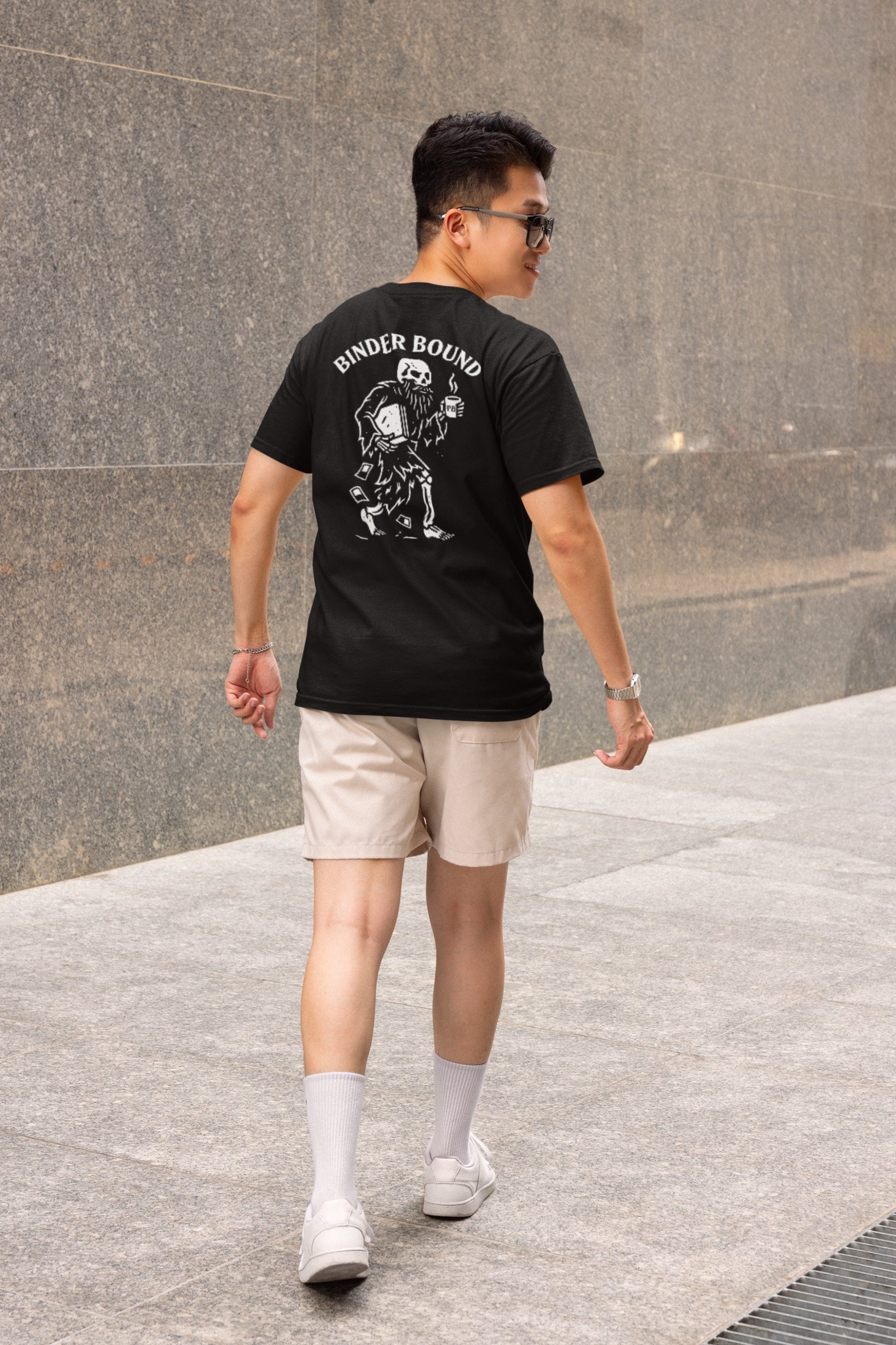 Man wearing a black t-shirt with a graphic design, walking on a stone pavement.